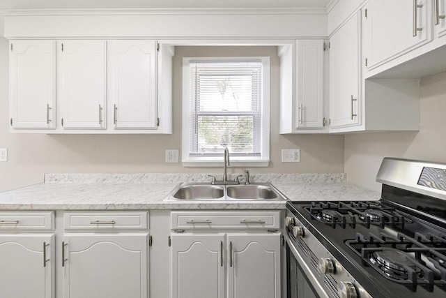 kitchen with stainless steel gas range oven, a sink, white cabinets, light countertops, and crown molding