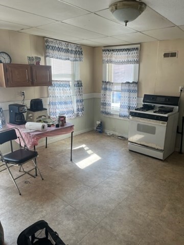 kitchen featuring a drop ceiling, tile patterned floors, and white gas range