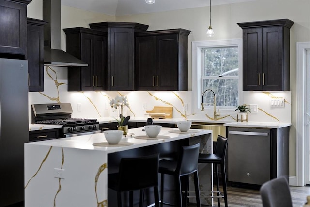 kitchen with appliances with stainless steel finishes, a kitchen island, dark hardwood / wood-style flooring, backsplash, and wall chimney exhaust hood