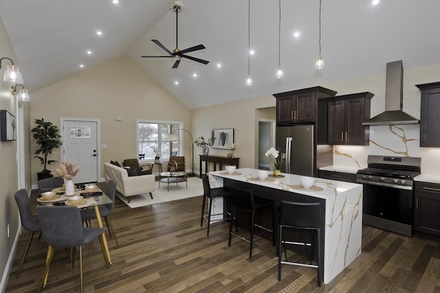 kitchen featuring a center island, a breakfast bar, wall chimney range hood, and appliances with stainless steel finishes