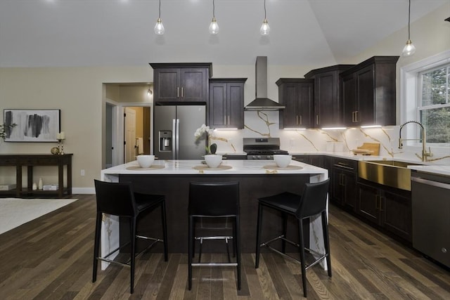 kitchen with a center island, sink, dark hardwood / wood-style flooring, stainless steel appliances, and wall chimney exhaust hood