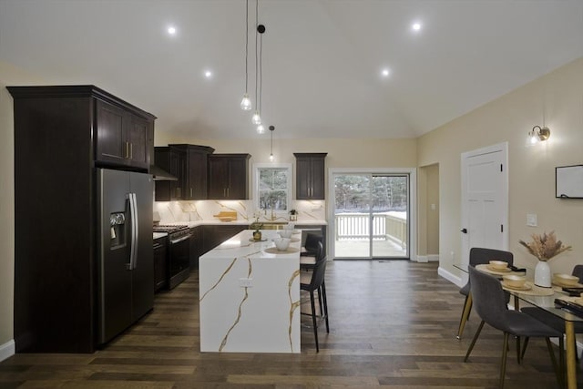 kitchen featuring a center island, a kitchen bar, appliances with stainless steel finishes, tasteful backsplash, and decorative light fixtures