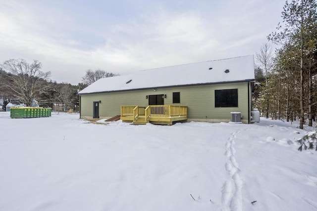 snow covered back of property featuring central AC unit and a wooden deck