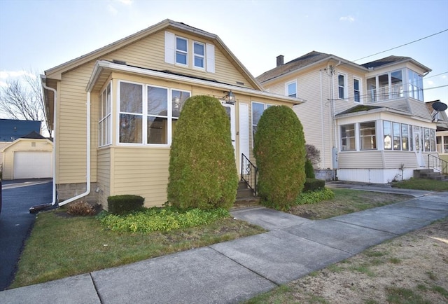 view of front facade featuring a sunroom, a garage, and an outdoor structure