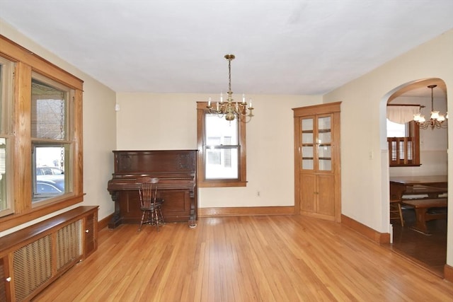 miscellaneous room featuring radiator, light wood-type flooring, a wealth of natural light, and a chandelier