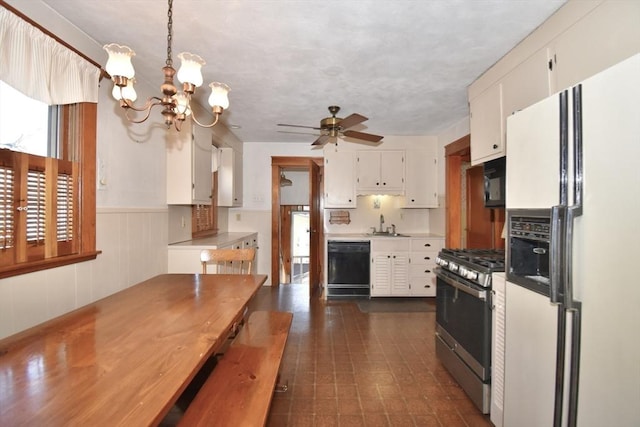 kitchen with ceiling fan with notable chandelier, sink, black appliances, decorative light fixtures, and white cabinetry