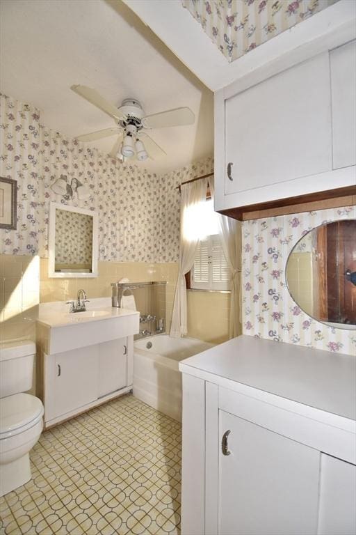 bathroom featuring vanity, toilet, ceiling fan, and a tub