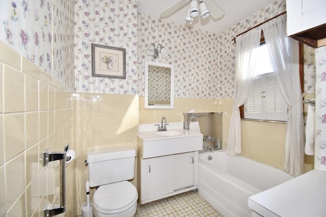 full bathroom with ceiling fan, tile walls, toilet, vanity, and shower / tub combo