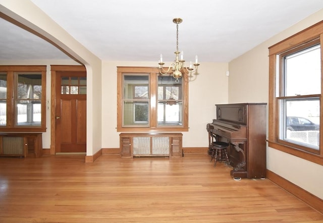 miscellaneous room with light hardwood / wood-style floors, radiator, and a chandelier