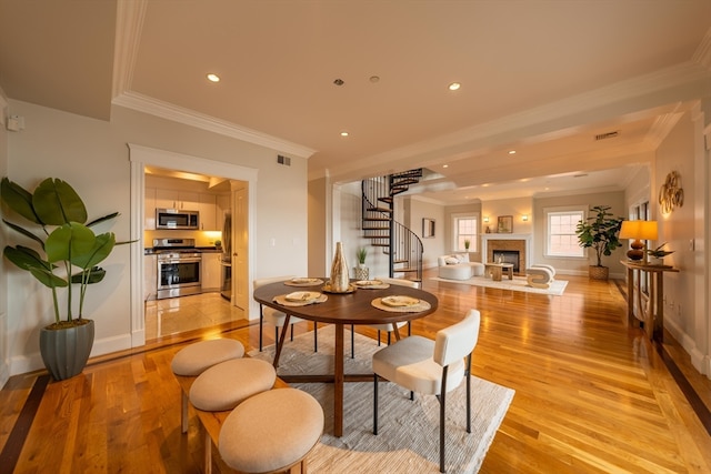 dining space with ornamental molding and light wood-type flooring