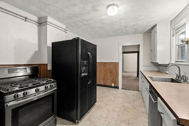 19-21 Pleasant St, North Andover, MA 01845 - kitchen with appliances with stainless steel finishes, a sink, wainscoting, wooden walls, and a textured ceiling