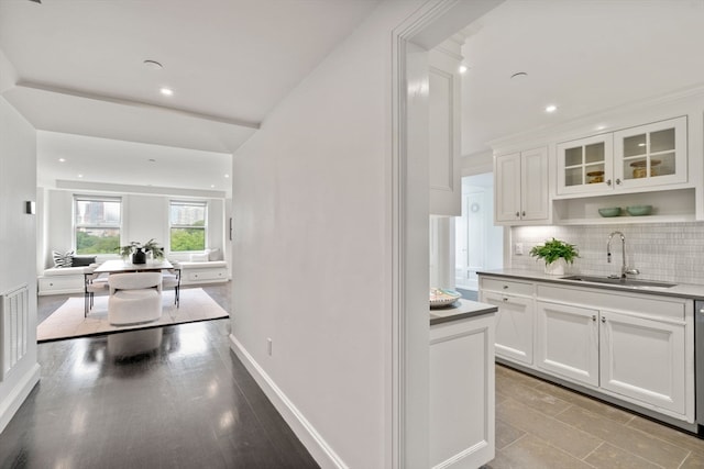 kitchen with white cabinetry, sink, backsplash, and light hardwood / wood-style flooring