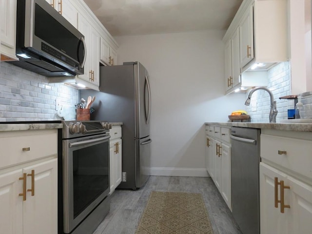 kitchen with white cabinetry, appliances with stainless steel finishes, light hardwood / wood-style floors, and decorative backsplash