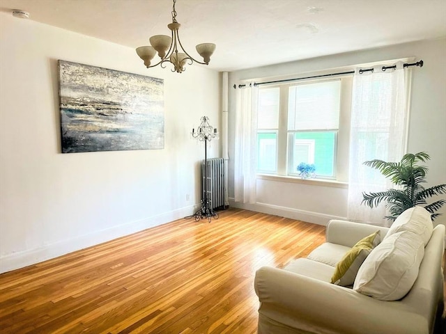 living area featuring hardwood / wood-style floors, radiator, and a chandelier