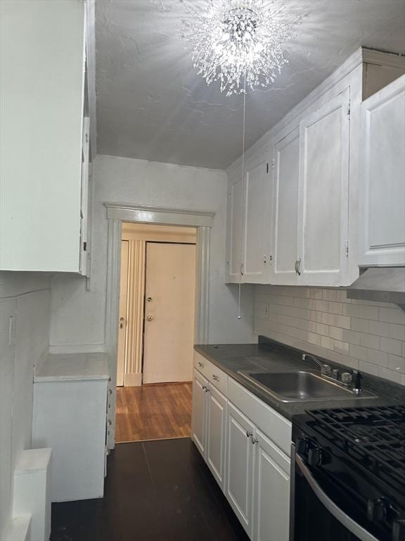 kitchen featuring black stove, sink, dark hardwood / wood-style floors, a notable chandelier, and white cabinetry