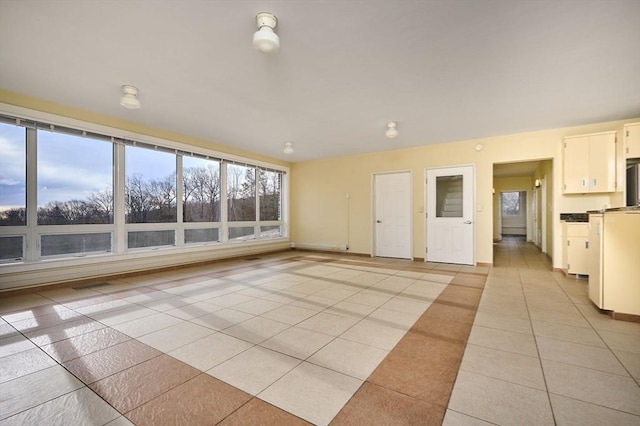 unfurnished living room featuring light tile patterned flooring, visible vents, and baseboards