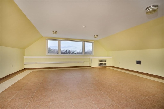 additional living space featuring visible vents, baseboards, and vaulted ceiling