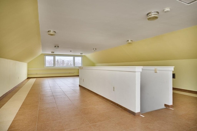 additional living space featuring light tile patterned flooring, baseboards, and lofted ceiling