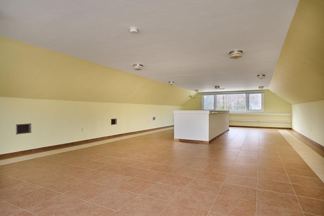 additional living space featuring light tile patterned floors, visible vents, and lofted ceiling