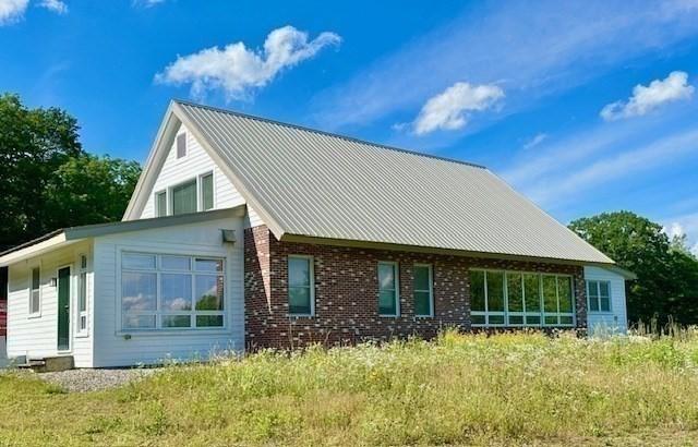 back of house featuring brick siding and metal roof