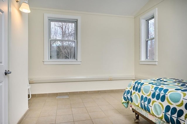 tiled bedroom featuring multiple windows and baseboards