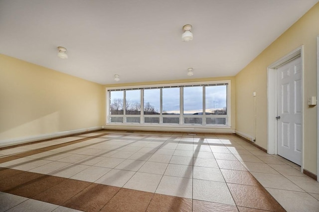 spare room with baseboards and light tile patterned flooring