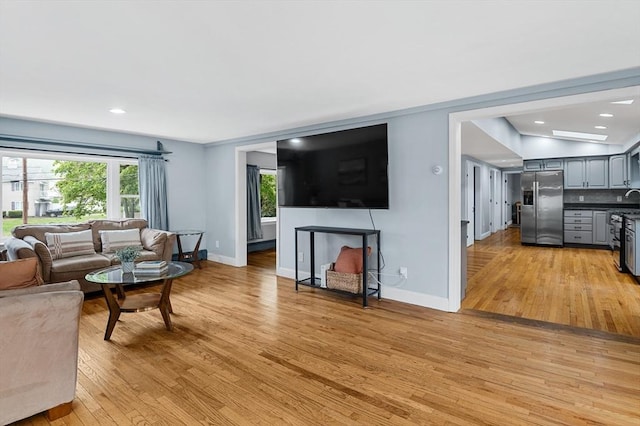 living room featuring light wood-type flooring, baseboards, and recessed lighting