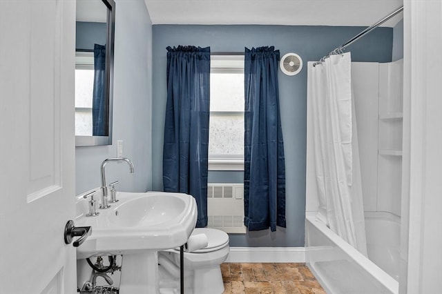 full bath featuring stone finish floors, radiator heating unit, toilet, shower / bathtub combination with curtain, and a sink