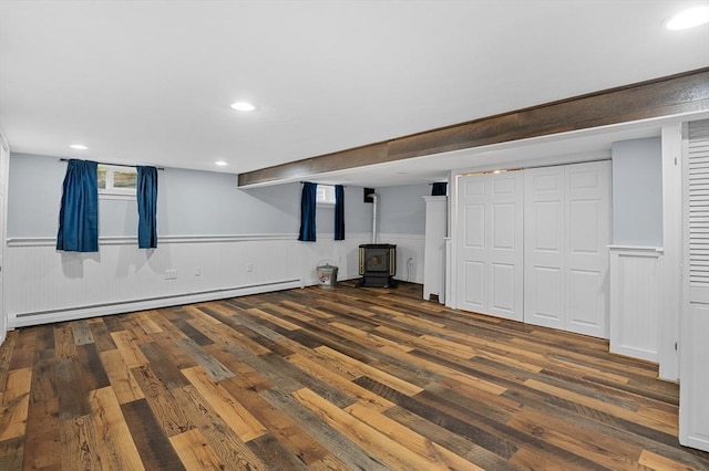 below grade area with baseboard heating, a wood stove, wood finished floors, wainscoting, and recessed lighting