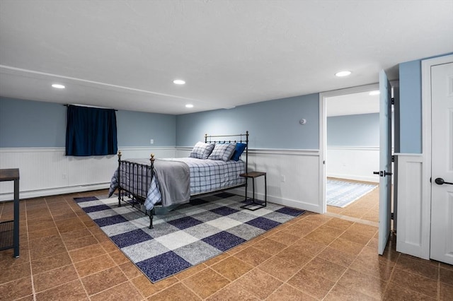 bedroom with a wainscoted wall, a baseboard radiator, and recessed lighting