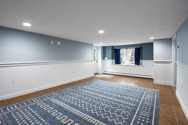 corridor featuring a baseboard heating unit, a wainscoted wall, tile patterned floors, and recessed lighting