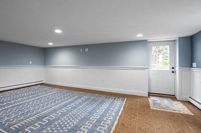 below grade area with wainscoting, a baseboard radiator, and recessed lighting