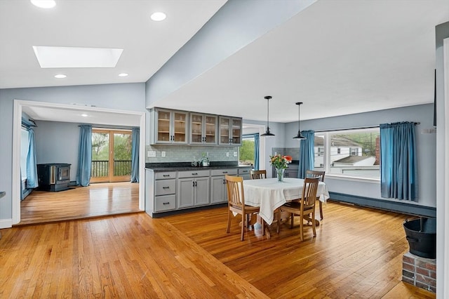 dining space with light wood-type flooring, a baseboard heating unit, a skylight, recessed lighting, and a wood stove