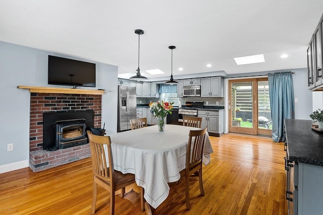 dining area with light wood-style floors, a skylight, healthy amount of natural light, recessed lighting, and baseboards