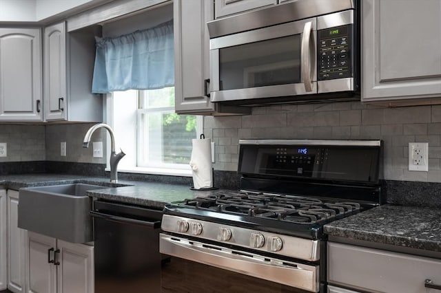 kitchen with stainless steel appliances, decorative backsplash, a sink, and white cabinetry
