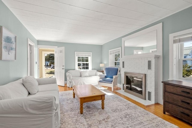 living room featuring a brick fireplace, plenty of natural light, and light wood-type flooring