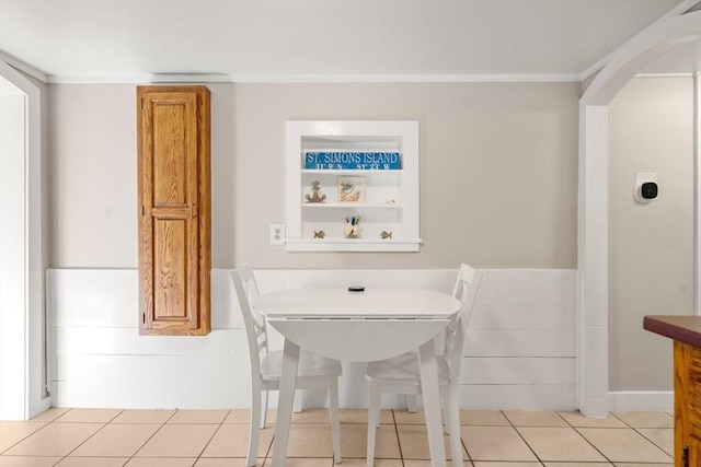 tiled dining space featuring crown molding