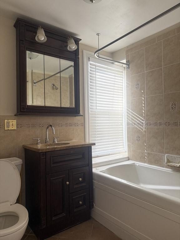 full bathroom with tile walls, vanity, toilet, a healthy amount of sunlight, and tile patterned floors