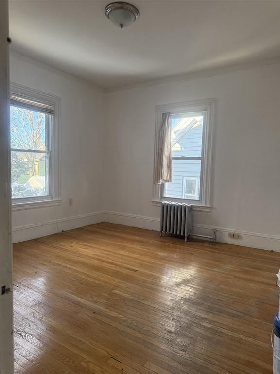 unfurnished room with ornamental molding, wood-type flooring, and radiator