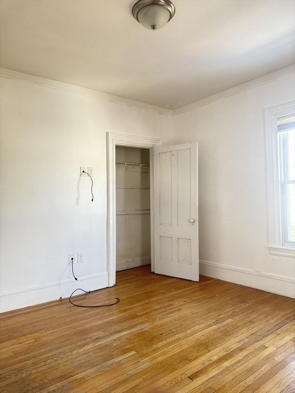 unfurnished bedroom featuring crown molding, light hardwood / wood-style flooring, and a closet