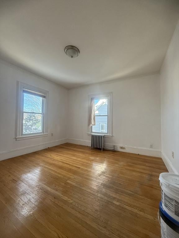 spare room featuring radiator, plenty of natural light, and hardwood / wood-style floors