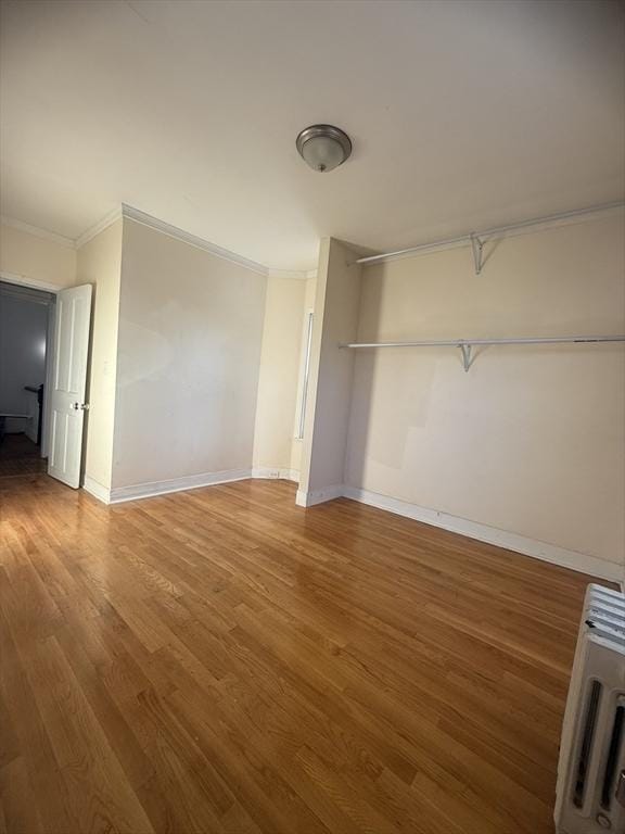 unfurnished bedroom featuring heating unit, hardwood / wood-style floors, and ornamental molding