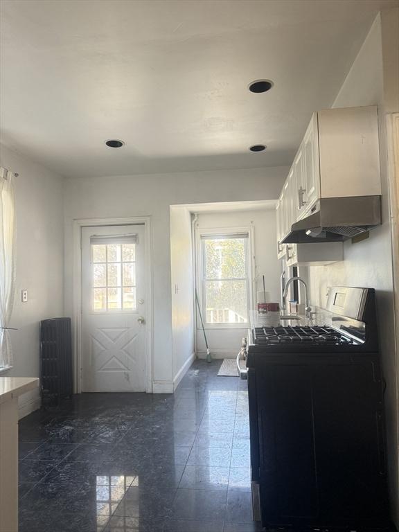 kitchen with gas range, sink, and white cabinets