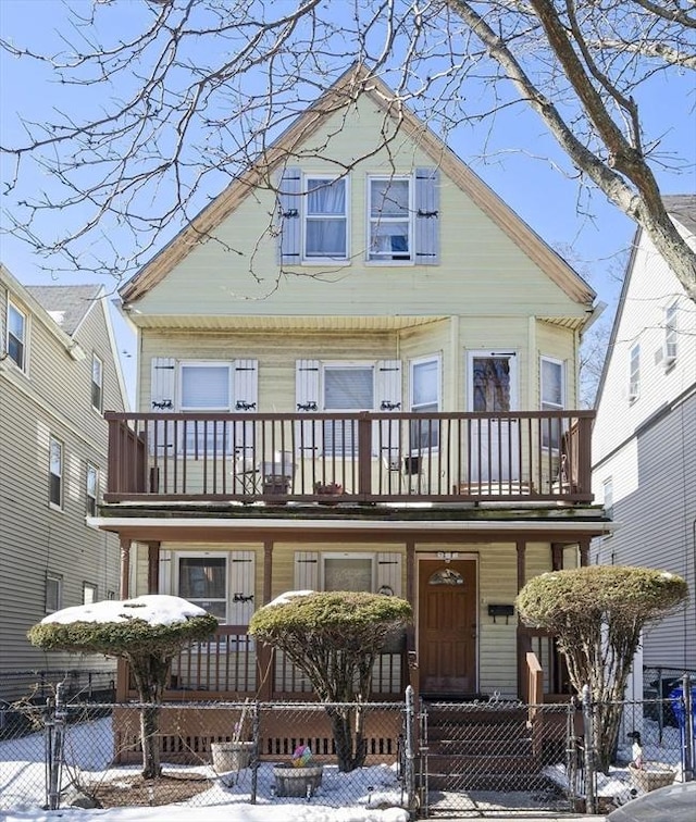 view of front facade with a fenced front yard, covered porch, a balcony, and a gate