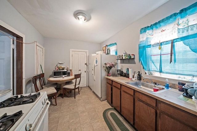 kitchen with light countertops, white appliances, and a sink