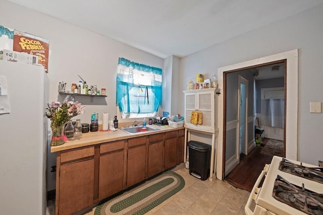 kitchen with white appliances, a sink, light countertops, brown cabinets, and open shelves