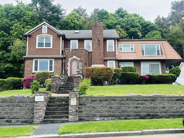 view of front of home featuring brick siding, a chimney, and a front lawn