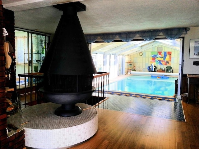 interior space featuring lofted ceiling, a wood stove, a textured ceiling, and hardwood / wood-style flooring