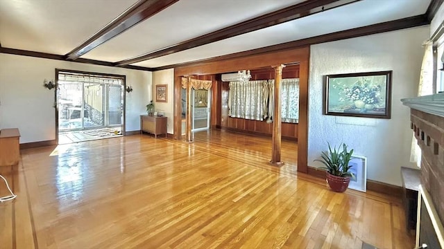 unfurnished living room featuring a fireplace, wood finished floors, baseboards, ornamental molding, and beamed ceiling