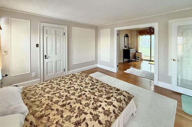 bedroom with ornamental molding, wood finished floors, and baseboards